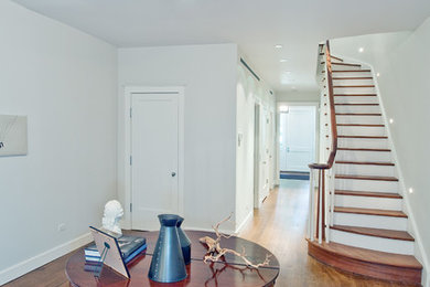 Example of a transitional medium tone wood floor foyer design in New York with white walls