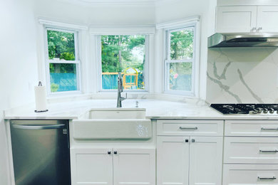 Example of a large trendy l-shaped porcelain tile, black floor and vaulted ceiling kitchen pantry design in New York with no island, a farmhouse sink, shaker cabinets, white cabinets, marble countertops, white backsplash, marble backsplash, stainless steel appliances and white countertops