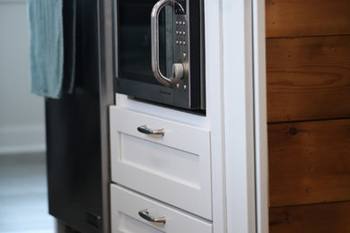Mid-sized cottage vinyl floor and gray floor kitchen photo in Other with a farmhouse sink, flat-panel cabinets, white cabinets, quartz countertops, gray backsplash, subway tile backsplash, stainless steel appliances, an island and white countertops