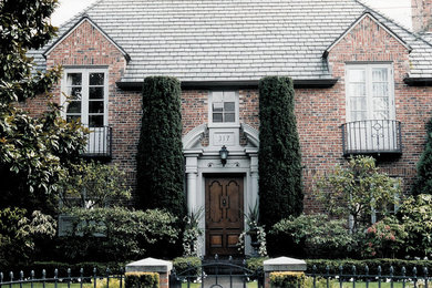Example of a mid-sized transitional red two-story brick exterior home design in Seattle with a clipped gable roof