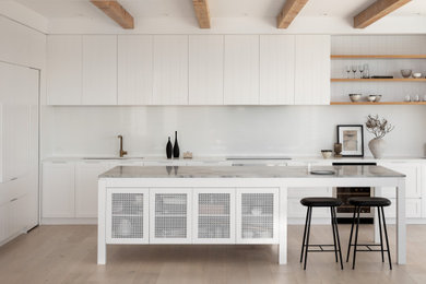 Inspiration for a contemporary open plan kitchen in Sydney with white cabinets, marble benchtops, white splashback, engineered quartz splashback, light hardwood floors, with island, white benchtop and exposed beam.