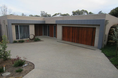 This is an example of a mid-sized modern one-storey brick house exterior in Melbourne with a flat roof and a metal roof.
