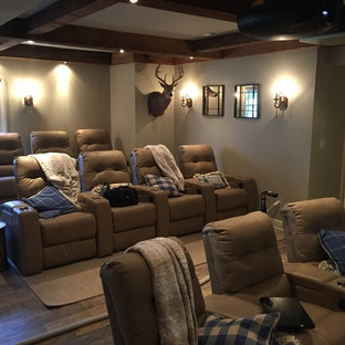 Cette image montre une grande salle de cinéma chalet ouverte avec un mur gris, un sol en bois brun, un écran de projection et un sol marron.