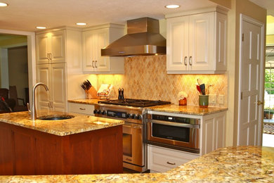 Large transitional u-shaped medium tone wood floor eat-in kitchen photo in Denver with an undermount sink, raised-panel cabinets, white cabinets, granite countertops, beige backsplash, ceramic backsplash, stainless steel appliances and an island