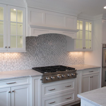 White Kitchen with Marble Counters, Glass Cabinets, and Geometric Backsplash