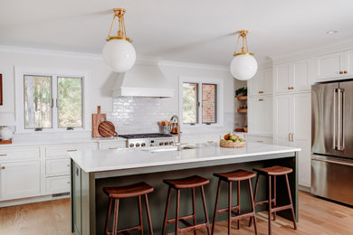 Inspiration for a mid-sized transitional l-shaped light wood floor eat-in kitchen remodel in Raleigh with a single-bowl sink, shaker cabinets, green cabinets, quartz countertops, white backsplash, subway tile backsplash, stainless steel appliances, an island and white countertops