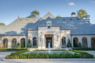 Design ideas for an expansive mediterranean beige exterior in Houston with stone veneer and a gable roof.