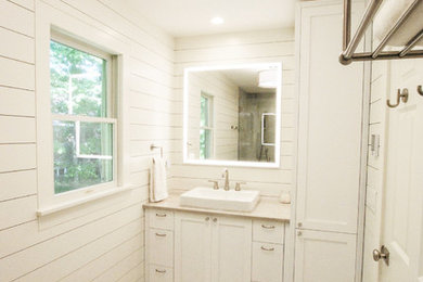 Mid-sized trendy gray tile and cement tile cement tile floor and gray floor doorless shower photo in New York with shaker cabinets, white cabinets, a one-piece toilet, white walls, a drop-in sink, marble countertops, a hinged shower door and beige countertops
