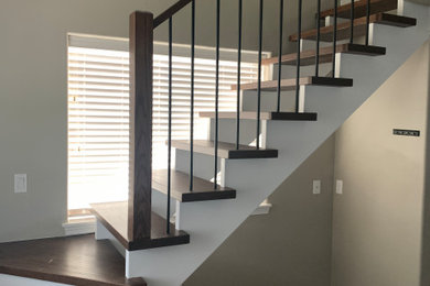 Diseño de escalera en L moderna grande sin contrahuella con escalones de madera y barandilla de varios materiales