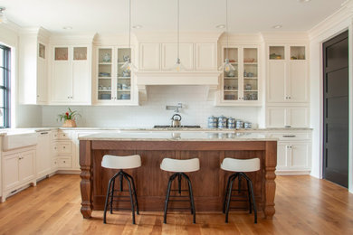 Inspiration for a l-shaped open concept kitchen remodel in Minneapolis with a farmhouse sink, flat-panel cabinets, white cabinets, white backsplash and an island