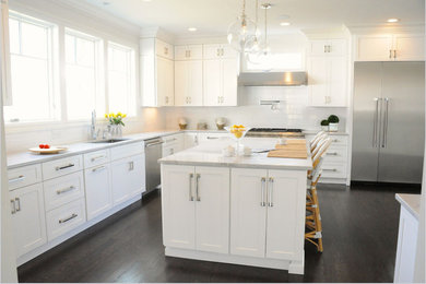 Photo of a large transitional u-shaped kitchen in New York with an undermount sink, shaker cabinets, white cabinets, marble benchtops, white splashback, subway tile splashback, stainless steel appliances, dark hardwood floors and with island.