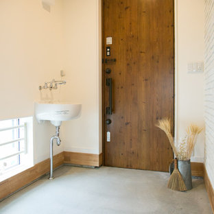 他の地域の大きい片開きドアコンテンポラリースタイルのおしゃれな玄関 (白い壁、コンクリートの床、木目調のドア、グレーの床) の写真