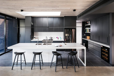 Photo of a large modern kitchen in Melbourne with flat-panel cabinets, quartz benchtops, white splashback, glass sheet splashback, stainless steel appliances, porcelain floors, with island, white benchtop, a double-bowl sink and black floor.