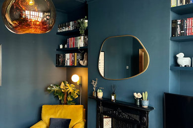 ロンドンにあるお手頃価格の中くらいなコンテンポラリースタイルのおしゃれな独立型リビング (青い壁、無垢フローリング、標準型暖炉、金属の暖炉まわり、壁掛け型テレビ、茶色い床) の写真