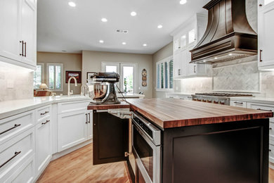 Example of a mid-sized transitional u-shaped light wood floor enclosed kitchen design in Los Angeles with recessed-panel cabinets, white cabinets, quartz countertops, white backsplash, marble backsplash, stainless steel appliances, an island and white countertops