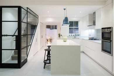 Photo of a large contemporary l-shaped eat-in kitchen in London with an undermount sink, flat-panel cabinets, white cabinets, quartzite benchtops, grey splashback, glass sheet splashback, stainless steel appliances, porcelain floors, with island and grey floor.
