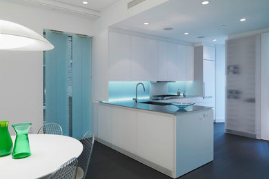 Inspiration for a mid-sized modern l-shaped dark wood floor and black floor eat-in kitchen remodel in New York with an undermount sink, paneled appliances, flat-panel cabinets, white cabinets, a peninsula, concrete countertops and gray backsplash