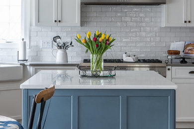 Kitchen - mid-sized transitional medium tone wood floor and brown floor kitchen idea in DC Metro with a farmhouse sink, shaker cabinets, white cabinets, quartz countertops, white backsplash, subway tile backsplash, stainless steel appliances and an island