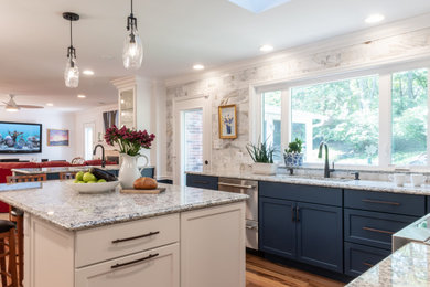 Photo of a large beach style l-shaped open plan kitchen in St Louis with an undermount sink, flat-panel cabinets, blue cabinets, granite benchtops, grey splashback, stone tile splashback, stainless steel appliances, medium hardwood floors, with island, brown floor and grey benchtop.