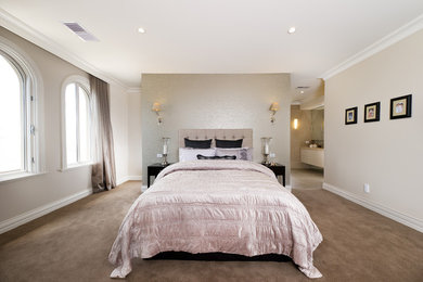 This is an example of a transitional master bedroom in Melbourne with beige walls, carpet and no fireplace.