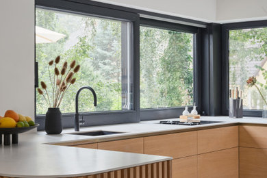 This is an example of an expansive modern grey and white u-shaped kitchen/diner in Berlin with flat-panel cabinets, wood worktops, white splashback, black appliances, no island and grey worktops.