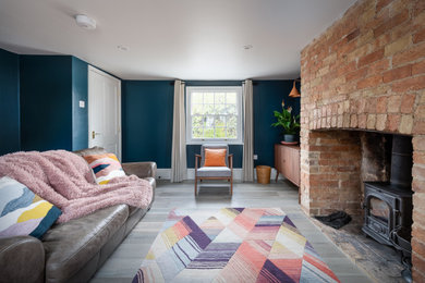 Inspiration for a medium sized contemporary enclosed living room in Cambridgeshire with blue walls, light hardwood flooring, a brick fireplace surround and brown floors.