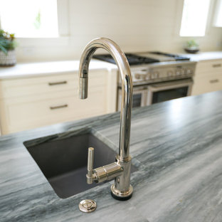 This is an example of a mid-sized transitional l-shaped eat-in kitchen in Charleston with an undermount sink, shaker cabinets, white cabinets, quartzite benchtops, white splashback, shiplap splashback, panelled appliances, medium hardwood floors, with island, brown floor and black benchtop.