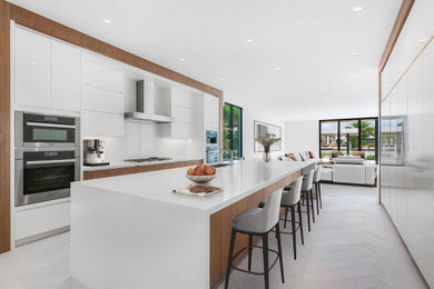 Kitchen - huge contemporary u-shaped gray floor kitchen idea in Miami with an undermount sink, flat-panel cabinets, white cabinets, white backsplash, stainless steel appliances, an island and white countertops