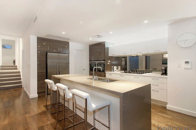 Photo of a contemporary l-shaped open plan kitchen in Perth with an undermount sink, flat-panel cabinets, white cabinets, stainless steel appliances and with island.