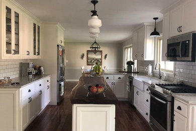 Mid-sized transitional galley laminate floor and brown floor eat-in kitchen photo in Other with a farmhouse sink, flat-panel cabinets, white cabinets, wood countertops, gray backsplash, subway tile backsplash, stainless steel appliances, an island and brown countertops