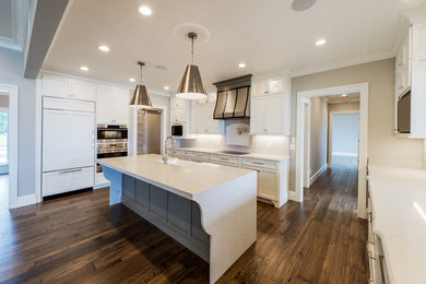Eat-in kitchen - mid-sized farmhouse single-wall dark wood floor and brown floor eat-in kitchen idea in Other with a farmhouse sink, shaker cabinets, white cabinets, quartz countertops, paneled appliances, an island and white countertops
