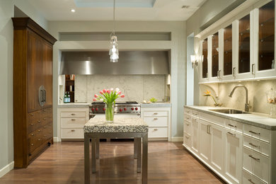 Example of a mid-sized transitional u-shaped medium tone wood floor enclosed kitchen design in Kansas City with an undermount sink, recessed-panel cabinets, white cabinets, marble countertops, gray backsplash, stone slab backsplash, stainless steel appliances and an island