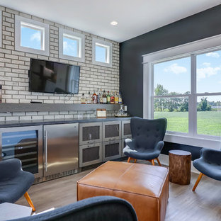 グランドラピッズの中サイズのコンテンポラリースタイルのおしゃれなウェットバー (家具調キャビネット、グレーのキャビネット、白いキッチンパネル、サブウェイタイルのキッチンパネル、淡色無垢フローリング、ベージュの床、グレーのキッチンカウンター、ドロップインシンク) の写真