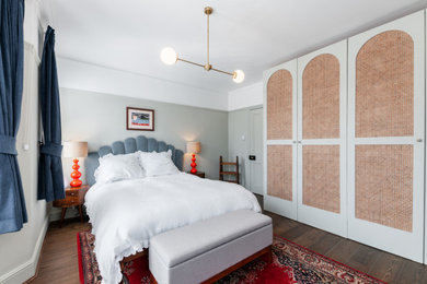 Diseño de dormitorio principal ecléctico grande con paredes grises, suelo de madera en tonos medios, todas las chimeneas, marco de chimenea de piedra y suelo marrón