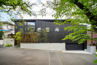 This is an example of a modern split-level black house exterior in Yokohama with wood siding, a shed roof and a metal roof.