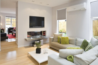 Photo of a mid-sized contemporary open concept living room in Auckland with grey walls, a two-sided fireplace, a wall-mounted tv and beige floor.