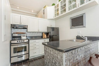 Inspiration for a small transitional single-wall open concept kitchen remodel in Orange County with a single-bowl sink, raised-panel cabinets, white cabinets, laminate countertops, gray backsplash, metal backsplash, stainless steel appliances and a peninsula