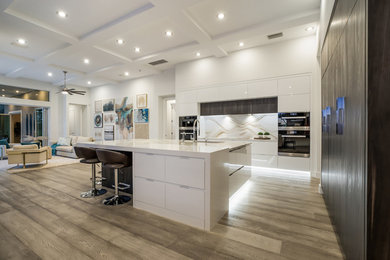 Example of a large minimalist l-shaped medium tone wood floor and gray floor eat-in kitchen design in Tampa with an undermount sink, flat-panel cabinets, white cabinets, quartz countertops, multicolored backsplash, stone slab backsplash, black appliances, an island and multicolored countertops