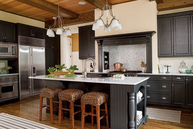 Large elegant galley medium tone wood floor open concept kitchen photo in New York with a farmhouse sink, recessed-panel cabinets, black cabinets, marble countertops, white backsplash, stone tile backsplash, stainless steel appliances and an island