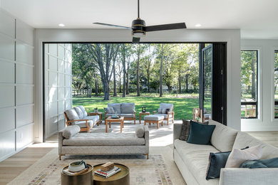Large minimalist open concept light wood floor living room photo in Other with white walls