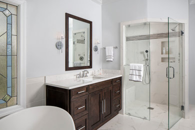 Inspiration for a large transitional master bathroom in Atlanta with recessed-panel cabinets, light wood cabinets, a freestanding tub, a corner shower, gray tile, white tile, porcelain tile, grey walls, porcelain floors, an undermount sink, white floor and a hinged shower door.