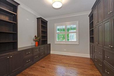 Mid-sized elegant built-in desk medium tone wood floor and brown floor home office photo in Other with gray walls