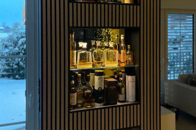 Inspiration for a small contemporary home bar in Munich with louvered cabinets and medium wood cabinets.