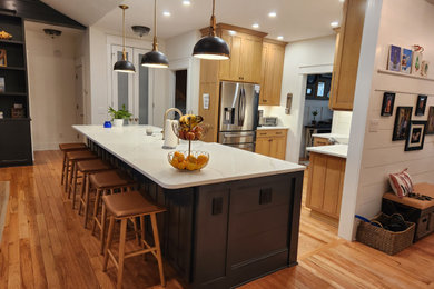 Eat-in kitchen - small transitional u-shaped light wood floor and yellow floor eat-in kitchen idea in Raleigh with a farmhouse sink, shaker cabinets, black cabinets, quartz countertops, white backsplash, ceramic backsplash, stainless steel appliances, an island and white countertops