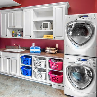 Design ideas for a medium sized classic single-wall separated utility room in Omaha with raised-panel cabinets, white cabinets, laminate countertops, red walls, porcelain flooring, a stacked washer and dryer and a built-in sink.