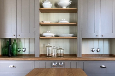 Diseño de cocina campestre de tamaño medio abierta con armarios estilo shaker, puertas de armario grises y encimera de madera