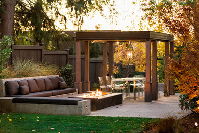 This is an example of a mid-sized contemporary backyard patio in Seattle with a fire feature, concrete slab and a pergola.