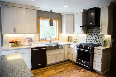 Mid-sized farmhouse l-shaped medium tone wood floor and brown floor kitchen photo in Other with a farmhouse sink, shaker cabinets, white cabinets, granite countertops, white backsplash, subway tile backsplash, black appliances and an island