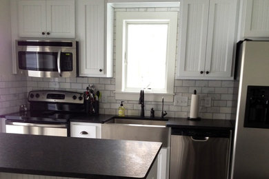 Kitchen - small country galley kitchen idea in Other with a farmhouse sink, shaker cabinets, white cabinets, granite countertops, white backsplash, marble backsplash, white appliances, no island and black countertops