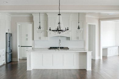 Large transitional dark wood floor and brown floor open concept kitchen photo in Minneapolis with an undermount sink, shaker cabinets, white cabinets, quartzite countertops, white backsplash, stainless steel appliances, an island, white countertops and ceramic backsplash